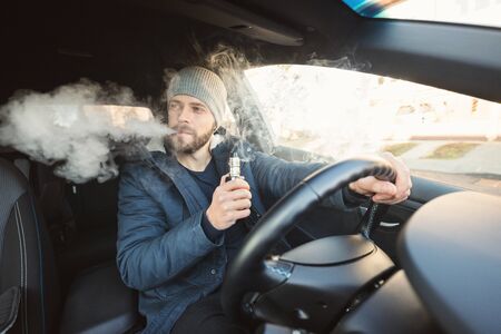 Vaping flavored e-liquid from an electronic cigarette in a carの写真素材