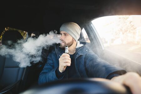 Vaping flavored e-liquid from an electronic cigarette in a carの写真素材