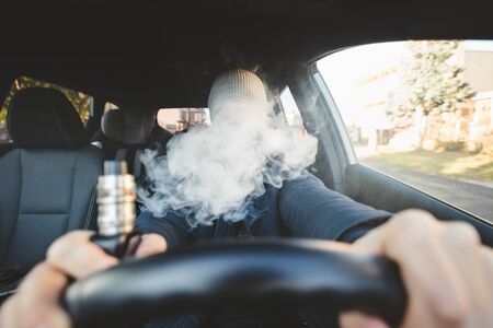 Vaping flavored e-liquid from an electronic cigarette in a carの写真素材