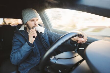 Vaping flavored e-liquid from an electronic cigarette in a carの写真素材