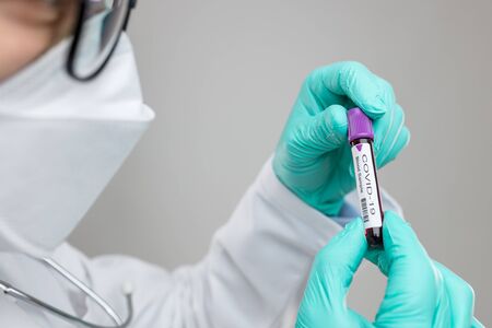 Doctor wearing respiratory mask and holding the Coronavirus Covid-19 blood sampleの写真素材