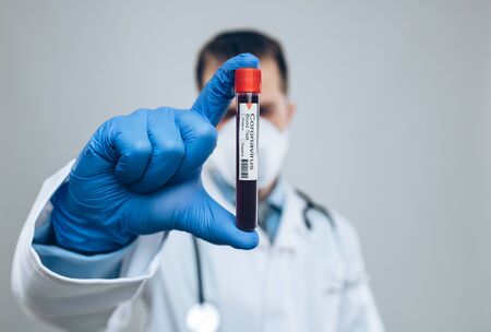Doctor wearing respiratory mask and holding the Coronavirus Covid-19 blood sampleの写真素材