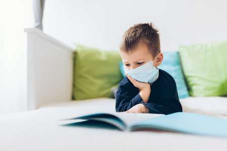 Unhappy young child wearing respiratory mask as prevention against the Coronavirus Covid-19の写真素材