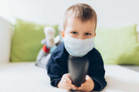 Unhappy young child wearing respiratory mask as prevention against the Coronavirus Covid-19の写真素材