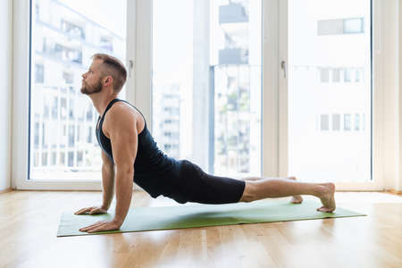 Young handsome man practicing yoga at homeの写真素材