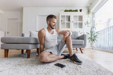 Handsome young man working out at home in the living room