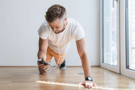 Handsome young man working out at home with a smart watchの写真素材