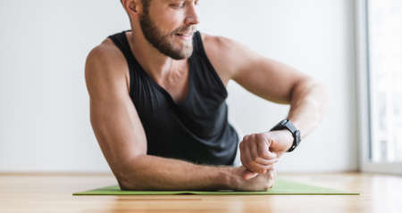 Handsome young man working out at home with a smart watchの写真素材