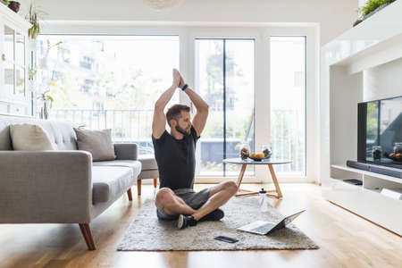 Handsome young man working out at home in the living roomの写真素材