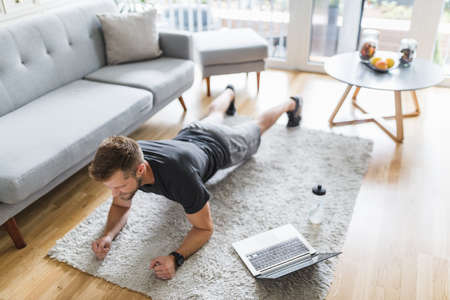 Handsome young man working out at home in the living room
