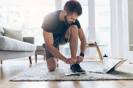 Handsome young man working out at home in the living roomの写真素材