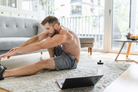 Handsome young man working out at home in the living roomの写真素材