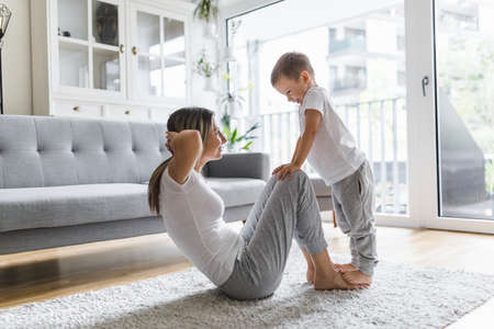 Mom with her young son working out in the living roomの写真素材