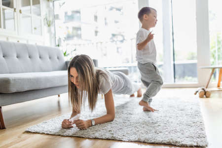 Mom with her young son working out in the living roomの写真素材