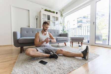 Handsome young man working out at home in the living roomの写真素材