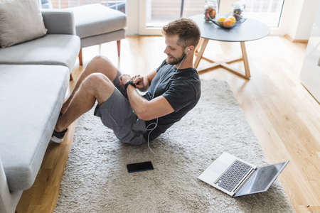 Handsome young man working out at home in the living roomの写真素材