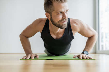 Handsome young man working out at home with a smart watchの写真素材