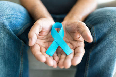 Senior man holding a blue cancer awareness ribbon in handの写真素材