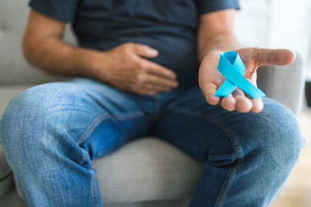 Senior man holding a blue cancer awareness ribbon in handの写真素材