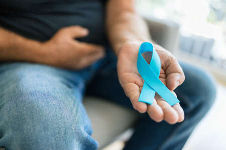 Senior man holding a blue cancer awareness ribbon in handの写真素材