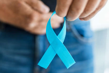 Senior man holding a blue cancer awareness ribbon in handの写真素材