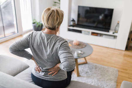 Elderly woman at home with lower back painの写真素材