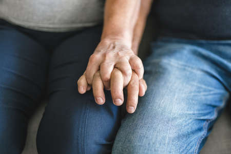 Happy romantic senior couple in love holding hands at homeの写真素材