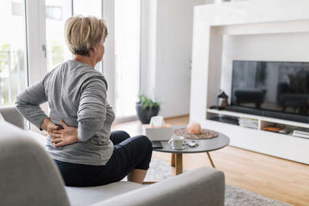 Elderly woman at home with lower back painの写真素材
