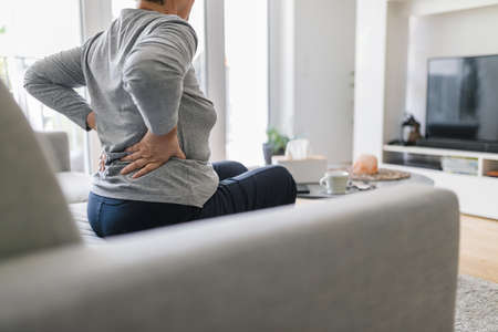Elderly woman at home with lower back painの写真素材