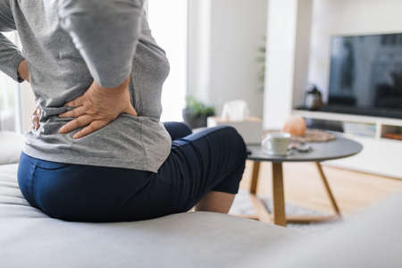 Elderly woman at home with lower back painの写真素材