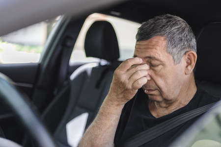 Tired pensioner in his 70s, dring in a carの写真素材