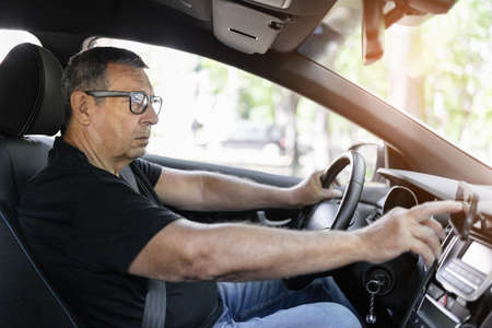 Senior behind the steering wheel using navigation and looking for directionsの写真素材