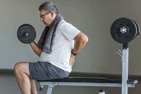 Active senior man in gym with back painの写真素材
