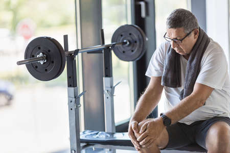 Active senior man in gym with knee injuryの写真素材