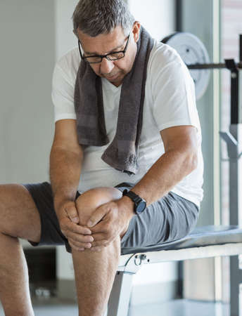 Active senior man in gym with knee injuryの写真素材