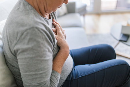 Elderly woman at home with heart pain holding her chestの写真素材