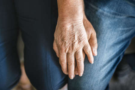 Happy romantic senior couple in love holding hands at homeの写真素材
