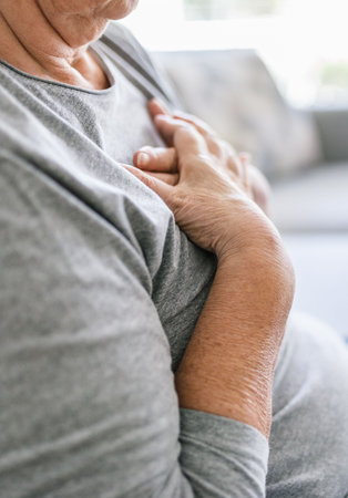 Elderly woman at home with heart pain holding her chestの写真素材
