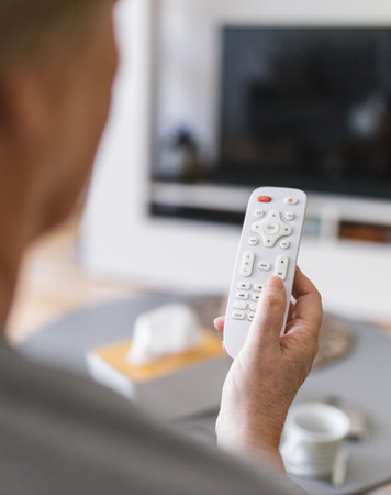 Senior woman with remote control watching televisionの写真素材