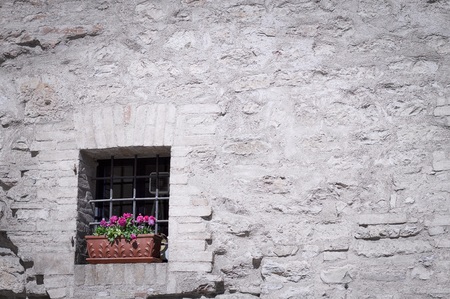 Isolated old window with a vase of violet flowers (Spello, Umbria, Italy)の写真素材