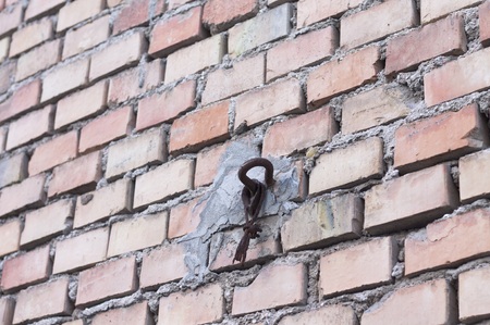 Rusted hook in a brick wall background (Pesaro, Italy)の写真素材