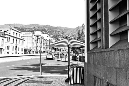 Funchal, Madeira, Portugal - August 16, 2019: A striped umbrella of food market in the corner of the streetの写真素材