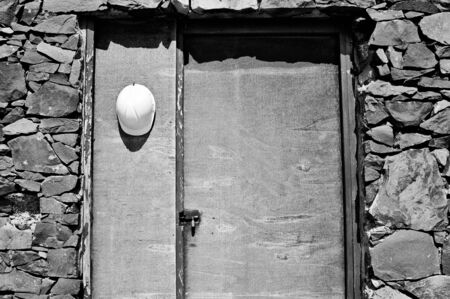 White worker with helmet hanging on a wooden door near the Atlantic Oceanの写真素材