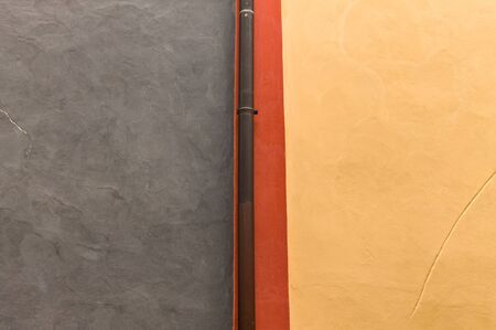Isolated metallic gutter tube in a blue, red and yellow wall background (Prague, Czech Republic,...