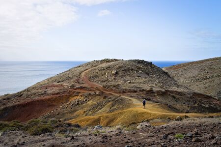 An adventurer is walking in desertic place near the Atlantic Ocean (Madeira, Portugal, Europe)の写真素材