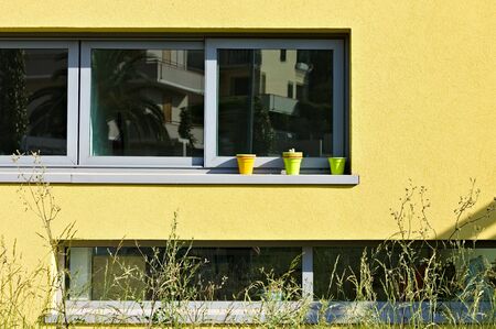 A yellow building with three little vases outside the window (Pesaro, Italy, Europe)の写真素材