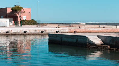 View of the harbor pier with a concrete staircase on the water (Pesaro, Italy, Europe)