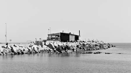 An old wooden building on the pier of the harbor in front of breakwaters on the Mediterranean sea...