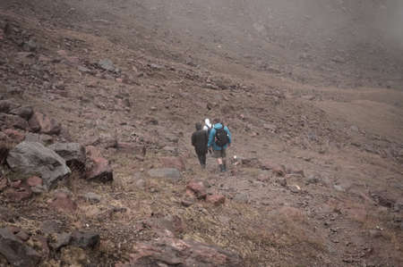 Three people are climbing a mountain on a foggy day on the italian Alps (Peio, Trentino - Alto Adige, Italy, Europe)の写真素材