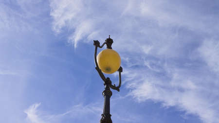 A spherical shaped vintage street lamp with metal decorations and the sky in background (Gubbio, Umbria, Italy)の写真素材